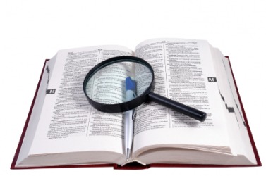 Open dictionary with a magnifying glass and pen on it