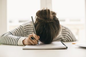 Woman pen in hand head on notebook