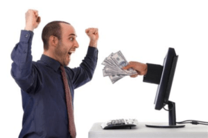 Hand holding money emerging from a computer screen to give the cash to an excited man