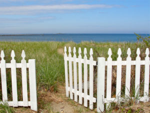 Open white picket gate by the ocean